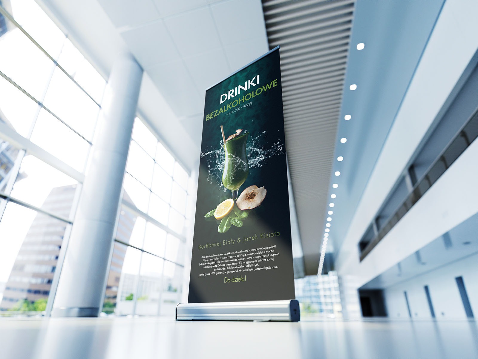 Roll-up reklamowy prezentujący bezalkoholowe drinki na tle nowoczesnego wnętrza biurowego, z widocznym szkłem z zielonym koktajlem, cytryną i gruszką.