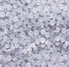 Zbliżenie na przezroczyste granulki tworzywa sztucznego o nieregularnych kształtach, tworzące jednolitą powierzchnię.