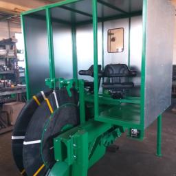 Turmet - Zielona konstrukcja metalowa z kabiną i podwójnymi kołami, prawdopodobnie element maszyny rolniczej, widoczne spawane łączenia i elementy mocujące.