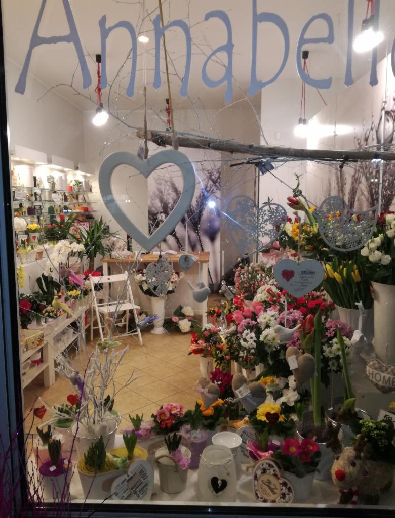 Dekoracyjna witryna kwiaciarni Annabelle we Wrocławiu, z różnorodnymi kwiatami w doniczkach i koszach, ozdobami w kształcie serc i napisem na szybie.