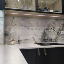 BergerDesign - Nowoczesna kuchnia z marmurowym blatem i szafkami z ekspozycją szkła. Bateria kuchenna i zlewozmywak wkomponowane w elegancki design. Dekoracje z muszelek w szklanym naczyniu.