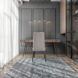 Nowoczesny pokój do pracy w Warszawie z biurkiem z szufladami na metalowych nogach, krzesłem tapicerowanym tkaniną w kolorze beżowym, szarą ścianą z trzema panelami, wiszącymi lampami z żarówkami...