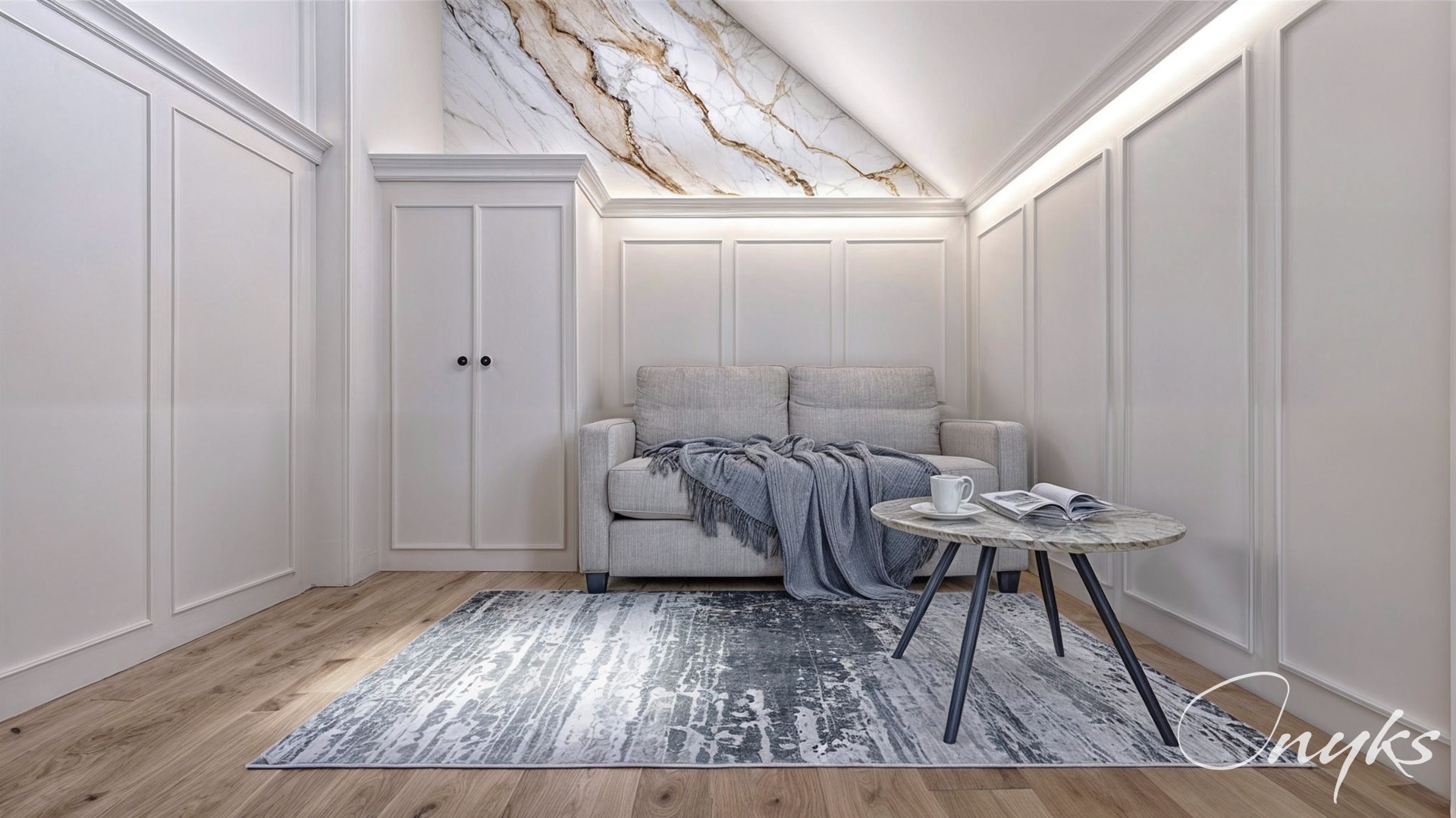 Jasny salon z marmurowym akcentem na skośnym suficie, sofa z szarym pledem, okrągły stolik z książką i filiżanką, wzorzysty dywan na drewnianej podłodze, białe ściany z dekoracyjnymi listwami.