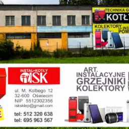 Budynek z reklamami zewnętrznymi kotł&oacute;w C.O., kolektor&oacute;w słonecznych i pomp ciepła, z widocznymi numerami telefon&oacute;w i adresem e-mail firmy.