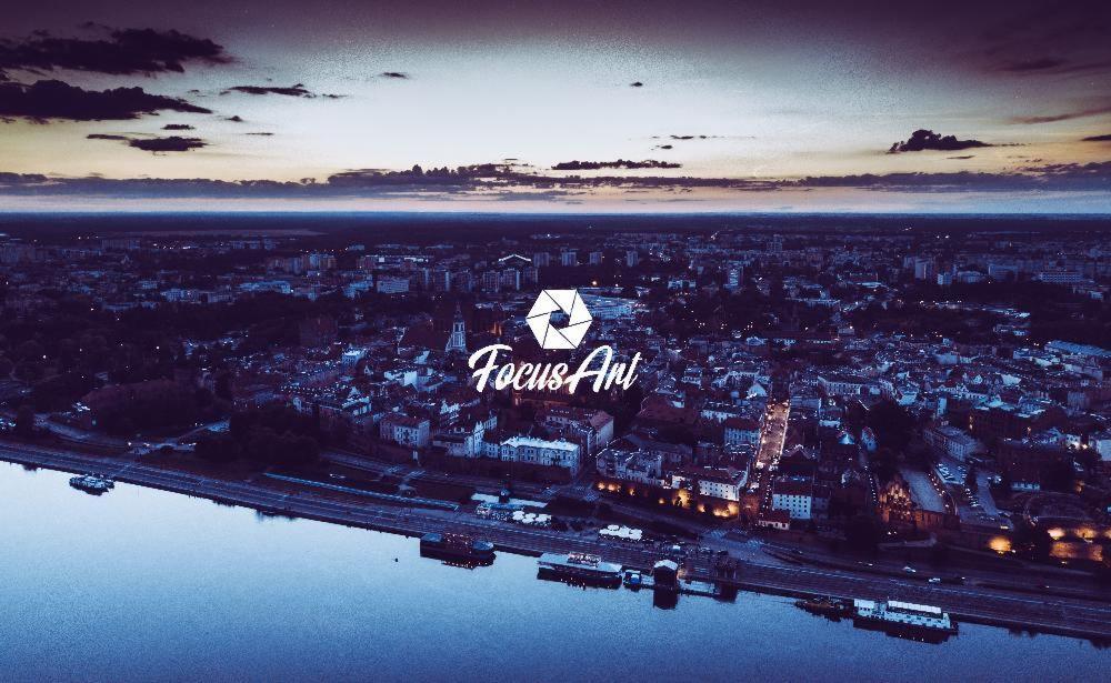 Panorama miasta z lotu ptaka o zmierzchu, z logo 'Focus Art' nałożonym na obraz.