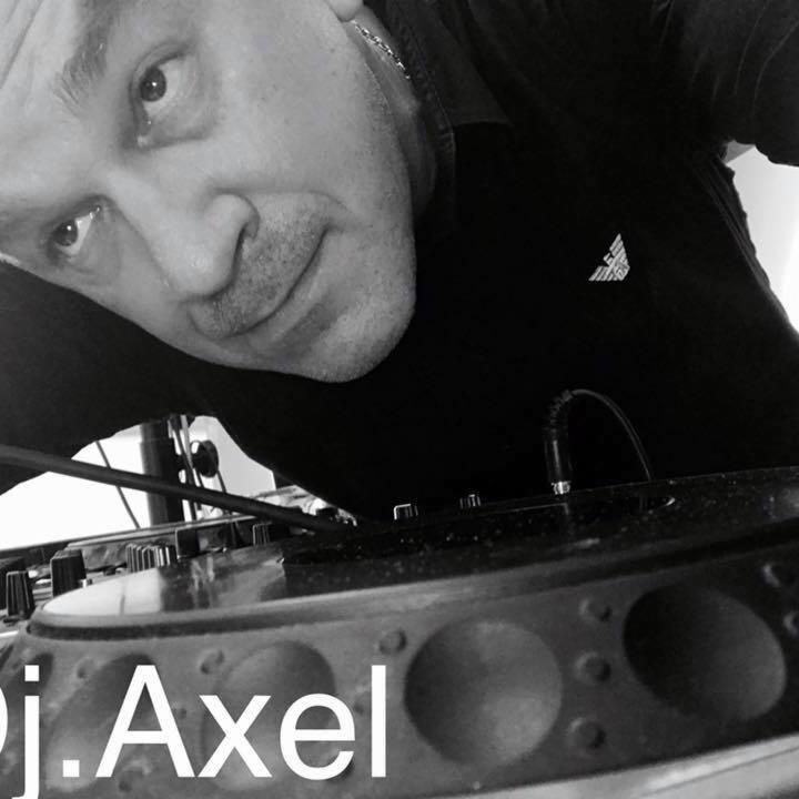 Czarno-białe zdjęcie DJ-a Axela pochylonego nad konsoletą, z widocznym logo na koszuli i podpisem artysty na pierwszym planie.