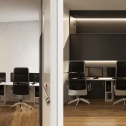 Nowoczesna przestrzeń biurowa z rzędem stanowisk komputerowych, każdy z czarnym monitorem i ergonomicznym krzesłem, oświetlona listwami LED, z podziałem na jasną i ciemną strefę.