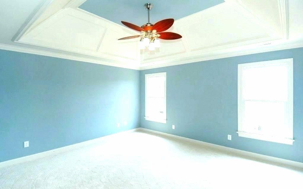 Pomalowane na niebiesko wnętrze pokoju z białym sufitem kasetonowym i wentylatorem sufitowym z czerwonymi łopatkami.