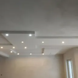 Nowoczesny sufit z płyt kartonowo-gipsowych z wbudowanym oświetleniem punktowym, świeżo wykończone ściany w jasnym odcieniu, widok z dołu.