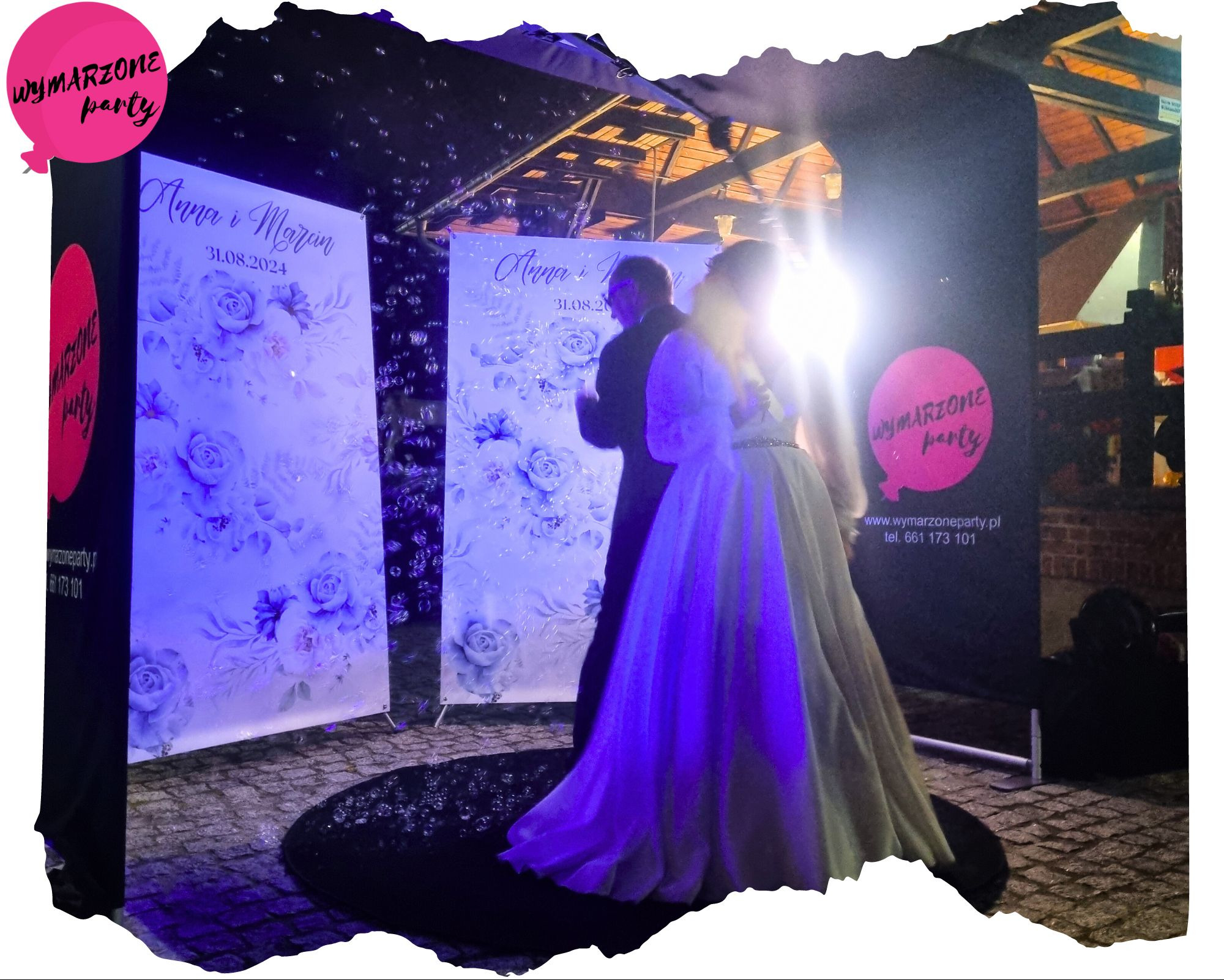 Para młoda pozuje przed fotobudką z motywem kwiatowym i datą ślubu, otoczoną bąbelkami mydlanymi, z widocznym logo firmy oferującej usługę.
