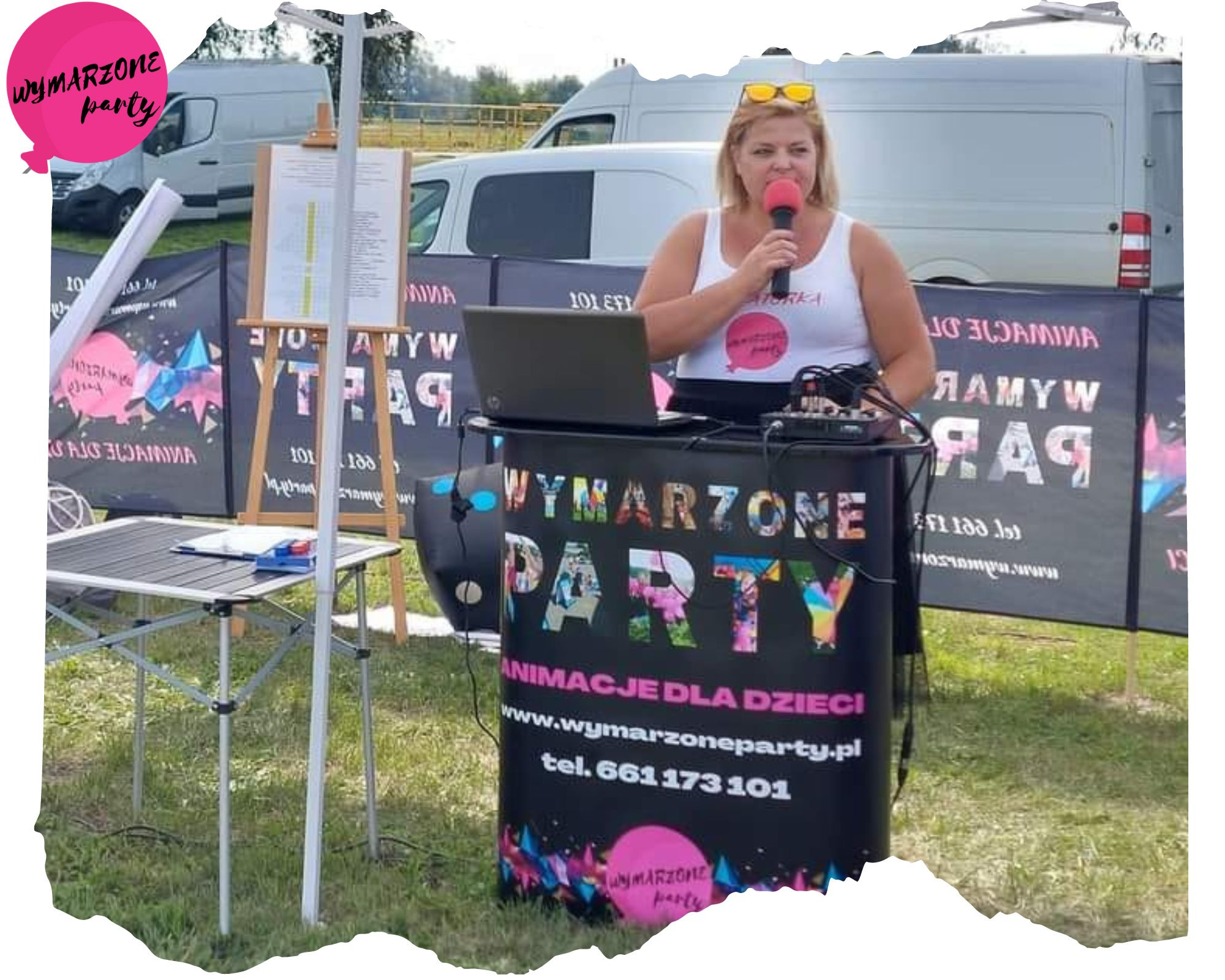 Kobieta z mikrofonem, laptopem i mikserem za ladą z napisem 'Wymarzone Party Animacje dla dzieci' podczas animacji na zewnątrz.