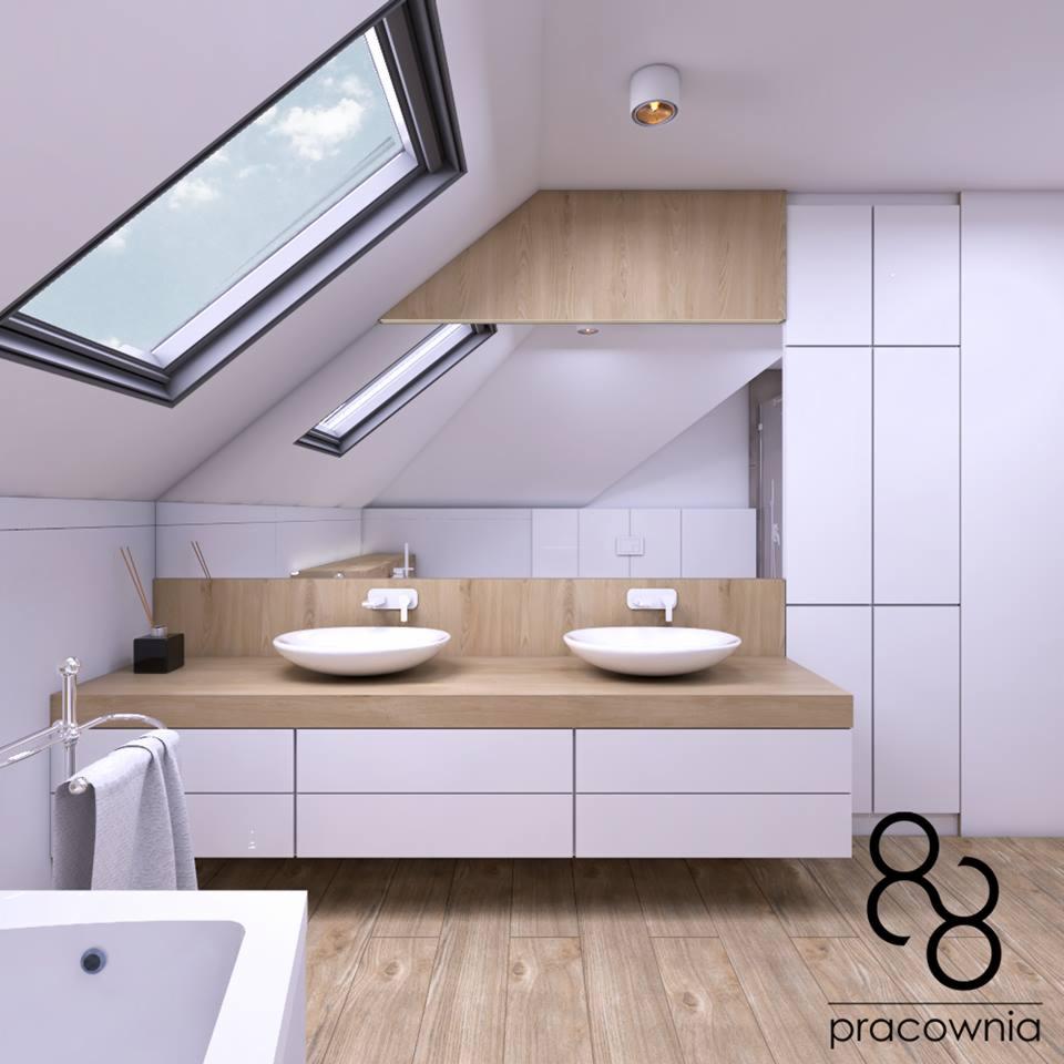 Nowoczesna łazienka na poddaszu z dwoma umywalkami nablatowymi, drewnianym blatem, białymi szafkami i oknami dachowymi w skośnym dachu, oświetlona punktowym światłem. Widoczne logo pracowni...