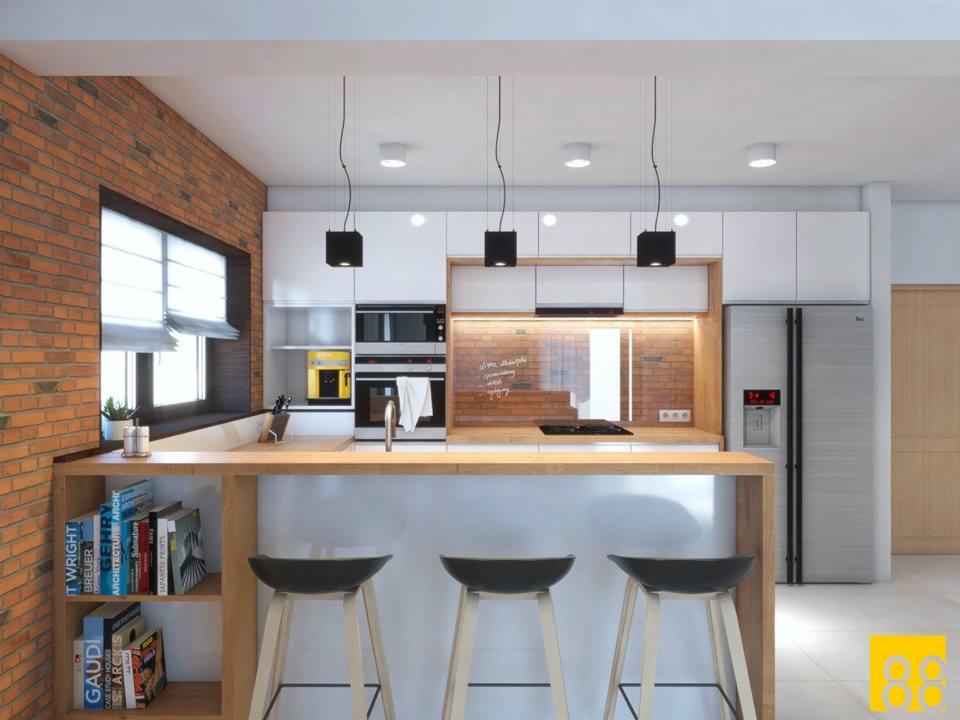 Nowoczesna kuchnia z ceglaną ścianą, białymi szafkami i drewnianym blatem, oświetlona trzema wiszącymi lampami, z trzema hokerami przy blacie i książkami na półce.
