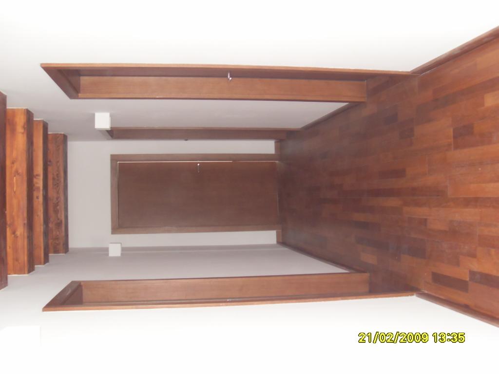 Wnętrze z drewnianą podłogą i obudową wnęki, widoczna klapa rewizyjna na ścianie, oświetlenie punktowe.