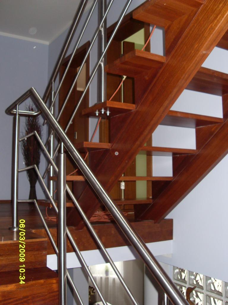 Nowoczesne schody drewniane z metalową balustradą w domu w Orzeszu, widok z dołu, jasne drewno stopni.