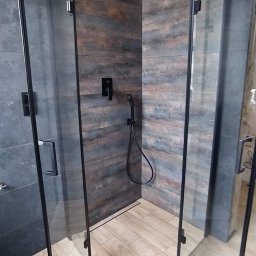 DAR-BUD Dariusz Kucharski - Nowoczesna kabina prysznicowa z czarnymi profilami, deszczownicą i baterią, wykończona płytkami imitującymi drewno i kamień.