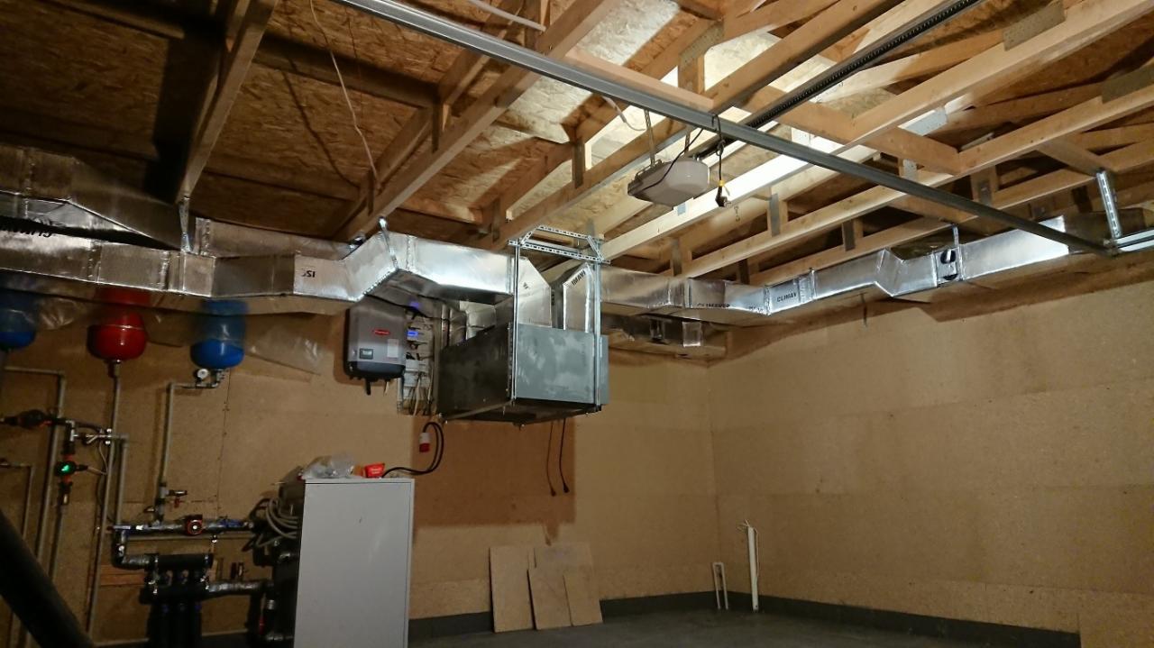 Instalacja kanałów wentylacyjnych z centralą w piwnicy, widoczne rury, zbiorniki i osprzęt kotłowni w tle.