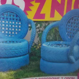 Dwa niebieskie fotele ogrodowe wykonane z opon, z oparciami z plecionki, stoją na trawie przed roślinami, zdjęcie z gazety.