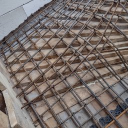 SPRINT-BUD Zbigniew Koloch - Siatka zbrojeniowa ułożona na drewnianym szalunku, widoczne dystanse z tworzywa sztucznego, przygotowanie do wylania betonu.