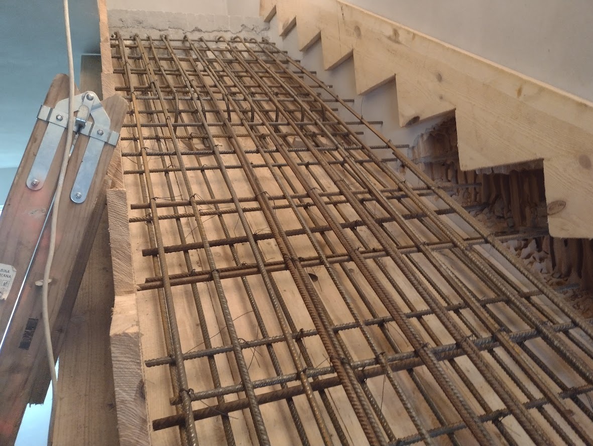Szkielet schodów z prętów zbrojeniowych w drewnianym szalunku, widoczne stopnie schodów w konstrukcji drewnianej.