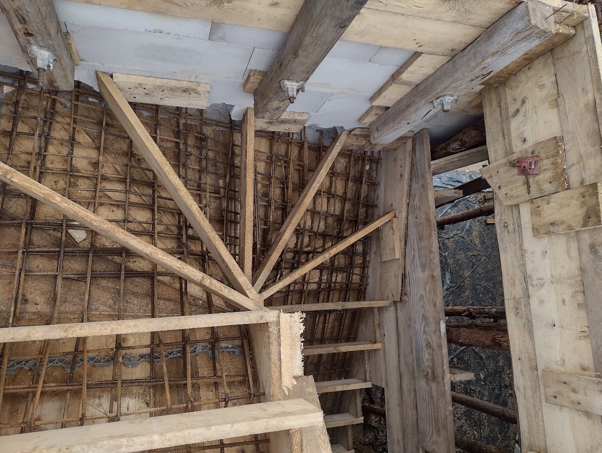 Zbrojenie schodów z drewnianym szalunkiem przed betonowaniem, widoczne elementy konstrukcyjne i stalowe pręty zbrojeniowe.