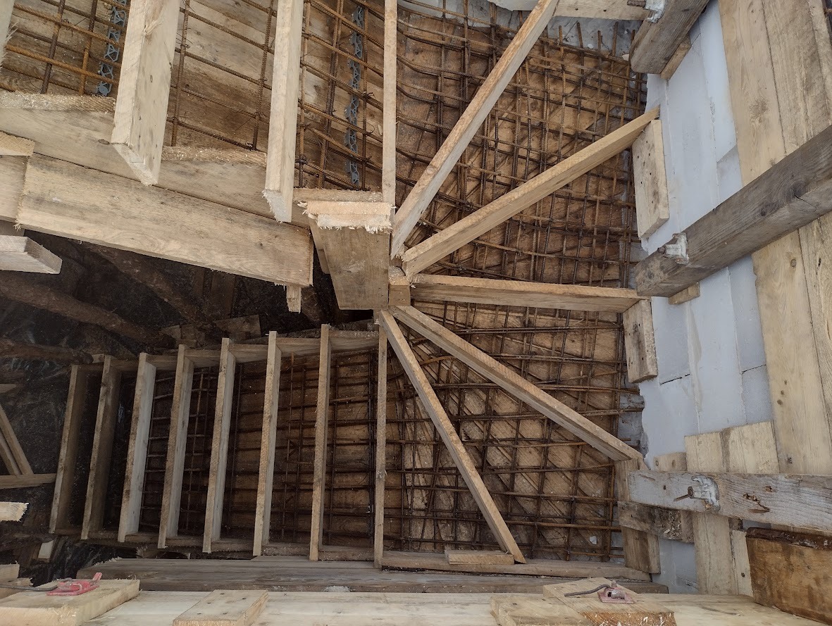 Konstrukcja szalunkowa i zbrojenie spiralnych schodów betonowych w trakcie budowy, widok z góry.