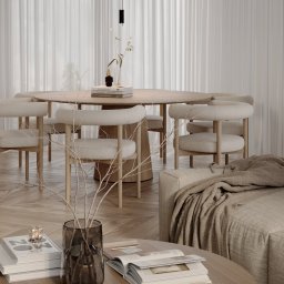 Sublime Studio Anna Pawelec - Jasne, minimalistyczne wnętrze: okrągły stół z krzesłami, drewniana podłoga, sofa z pledem i stolik kawowy z książkami. Całość w neutralnej palecie barw.