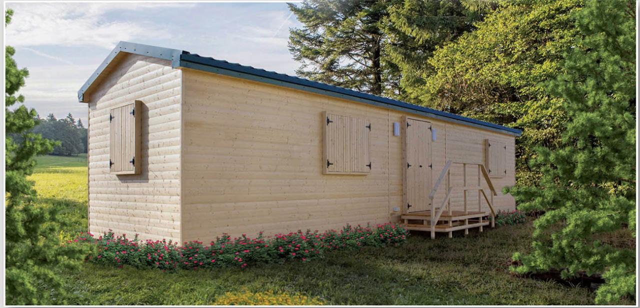 Gotowy, parterowy budynek z jasnego drewna z zadaszeniem, drewnianymi okiennicami i schodami wejściowymi, otoczony zielenią i kwiatami.