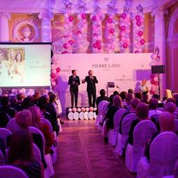 GATE.SP Z o.o. - Konferencja firmy Pierre Lang w eleganckiej sali z kolumnami, różowymi balonami i oświetleniem, dwóch prelegentów na scenie przed publicznością.