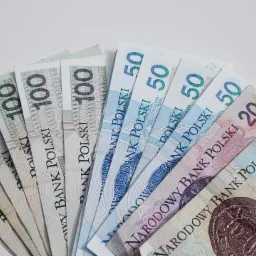 Rozłożone wachlarzem banknoty polskie o nominałach 100, 50, 20 i 10 złotych, ułożone na białym tle.