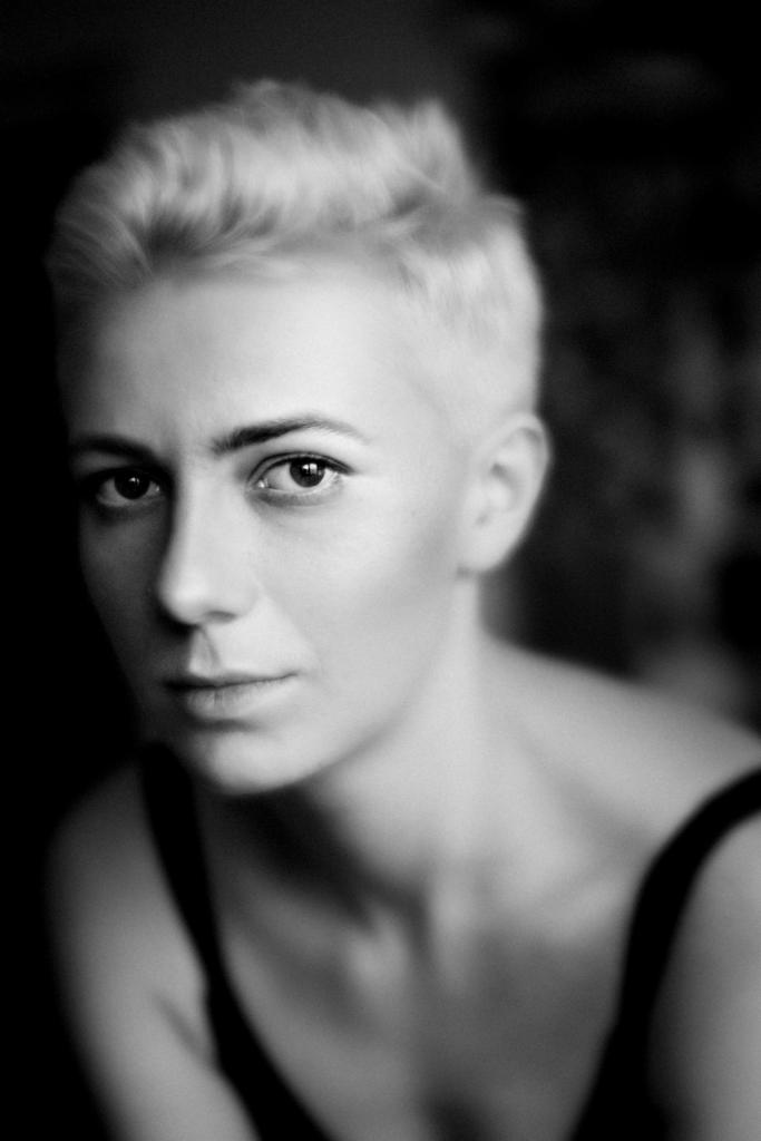 Czarno-biały portret kobiety z krótkimi blond włosami, wykonany w Łodzi z delikatnym oświetleniem bocznym, podkreślającym rysy twarzy i głębię spojrzenia.