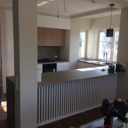 ANDREST.COM Paulina Andrzejewska - Wnętrze jasnej kuchni w trakcie montażu, widoczny fragment blatu z pionowymi listwami, narzędzia pracy na pierwszym planie, podłoga zabezpieczona folią.