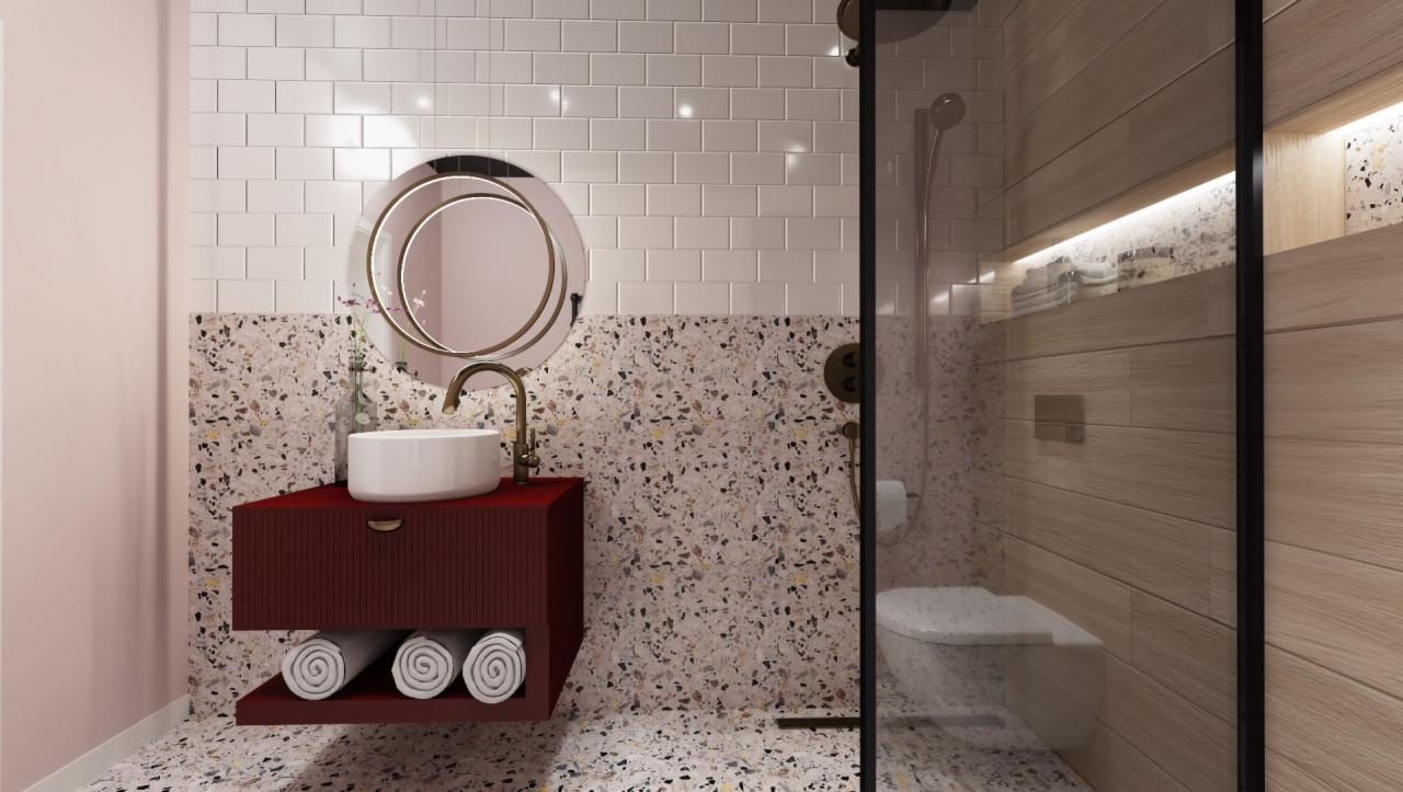 Nowoczesna łazienka z umywalką nablatową, okrągłym lustrem w złotej ramie, bordową szafką z półką na ręczniki, kabiną prysznicową z drewnopodobnymi płytkami i terazzo na ścianach oraz podłodze.