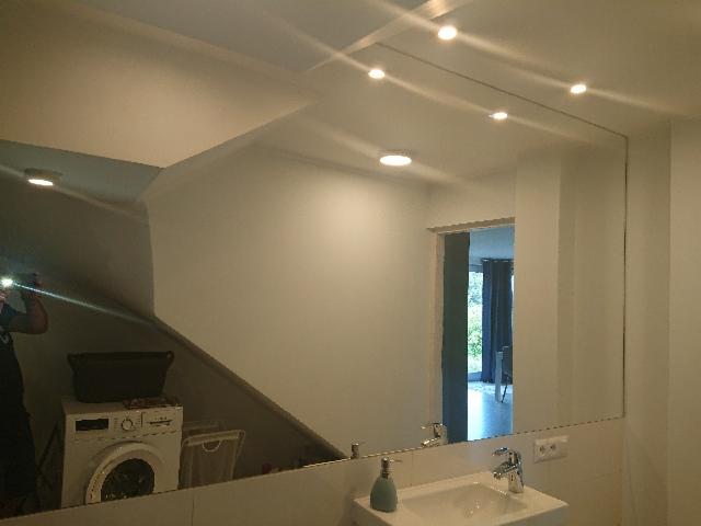 Duże lustro w łazience z widocznym odbiciem pralki i osoby robiącej zdjęcie.