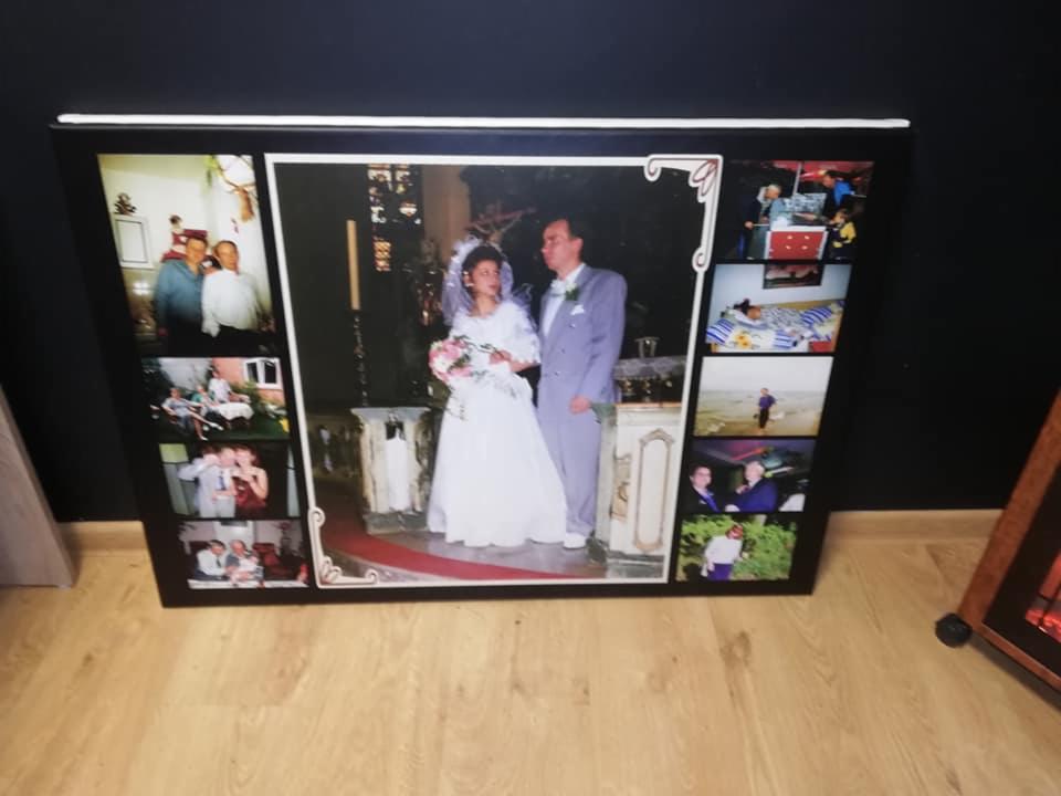 Duży, oprawiony w ramę kolaż zdjęć ślubnych, prezentujący różne momenty z uroczystości i wesela, ustawiony na podłodze.