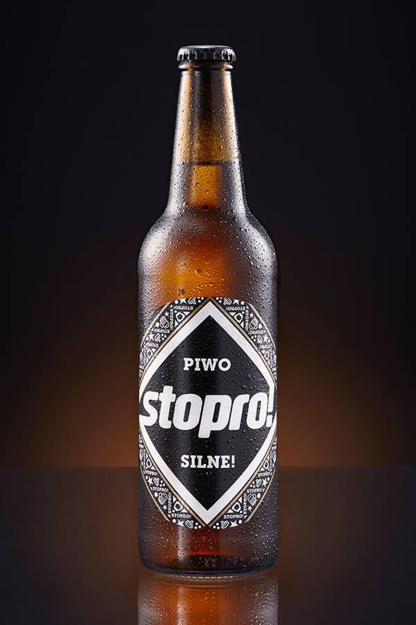 Butelka brązowego piwa Stopro z kroplami wody na etykiecie i butelce, na ciemnym tle.