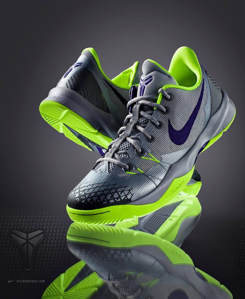 Para szaro-zielonych butów sportowych z fioletowym logo Nike, ustawionych na błyszczącej powierzchni z widocznym odbiciem.