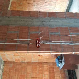 Ceglany strop z instalacją elektryczną w trakcie montażu, widoczne kable w peszlach i puszki instalacyjne.