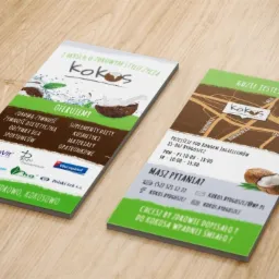 Dwa drukowane, dwustronne foldery reklamowe firmy 'Kokos' leżą na drewnianym blacie, prezentując ofertę zdrowej żywności, suplementów diety i kosmetyków, z mapką dojazdu do sklepu w Bydgoszczy.