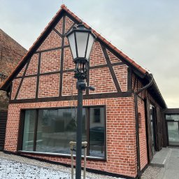 PBHU OBIEKT Sp. z o.o. - Nowoczesny dom murowany z elementami muru pruskiego, oświetlony starodawną latarnią, z widocznymi śladami śniegu.