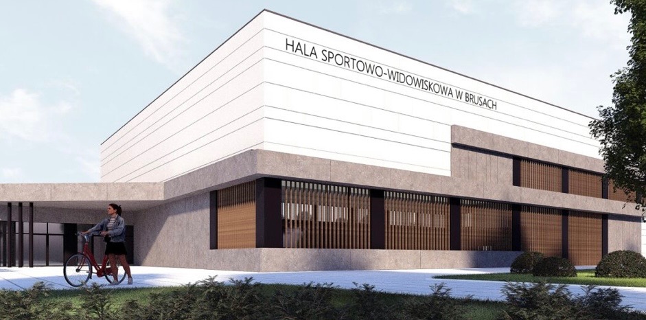 Wizualizacja hali sportowo-widowiskowej w Brusach z osobą prowadzącą rower przed wejściem, ukazująca nowoczesną architekturę z elementami betonowymi i drewnianymi żaluzjami.