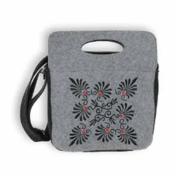 Szara filcowa torebka A4 z czarnym haftem w geometryczny wzór kwiatowy z czerwonymi akcentami, zapinana na zamek, z paskiem na ramię i uchwytem.