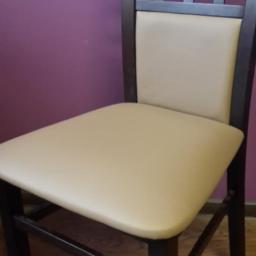 Produkcja i Renowacja Mebli BESUTO - Krzesło z ciemnego drewna z beżową tapicerką siedziska i oparcia, na tle fioletowej ściany, z charakterystyczną kratką w oparciu.