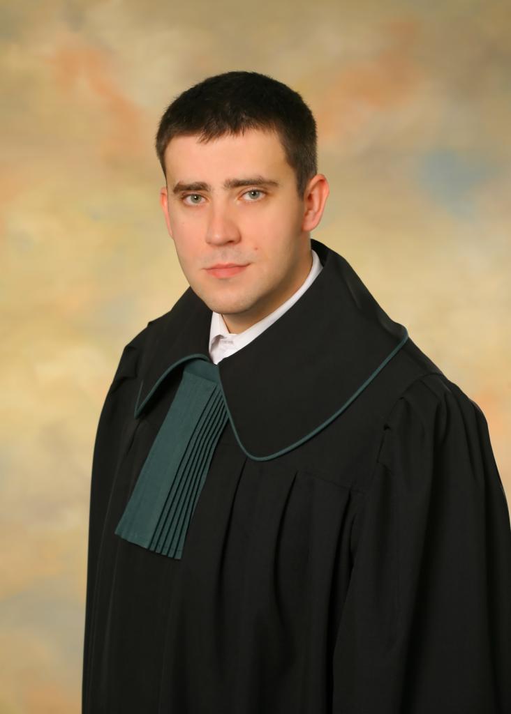 Portret mężczyzny w todze adwokackiej z zielonym żabotem na rozmytym, abstrakcyjnym tle.