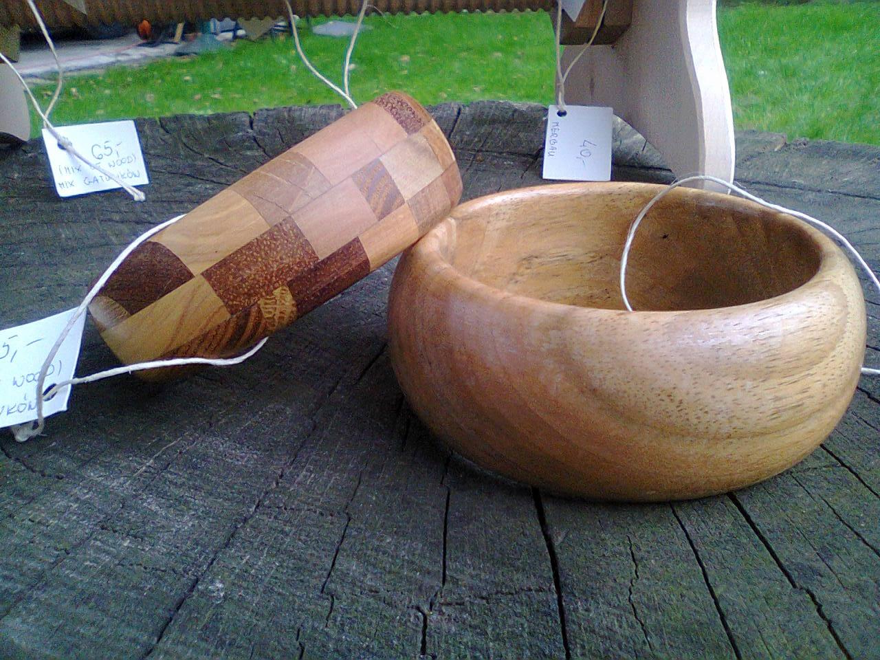 Ręcznie wykonana drewniana misa i pojemnik z patchworkowym wzorem, prezentowane na pniu drzewa z etykietami cenowymi.