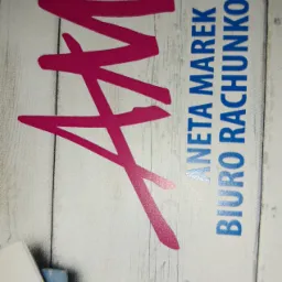 Wizytówka biura rachunkowego Aneta Marek z różowym logo na tle imitującym drewno.