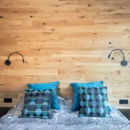 Dębowy panel za łóżkiem w połączeniu z czarnymi szafkami nocnymi.