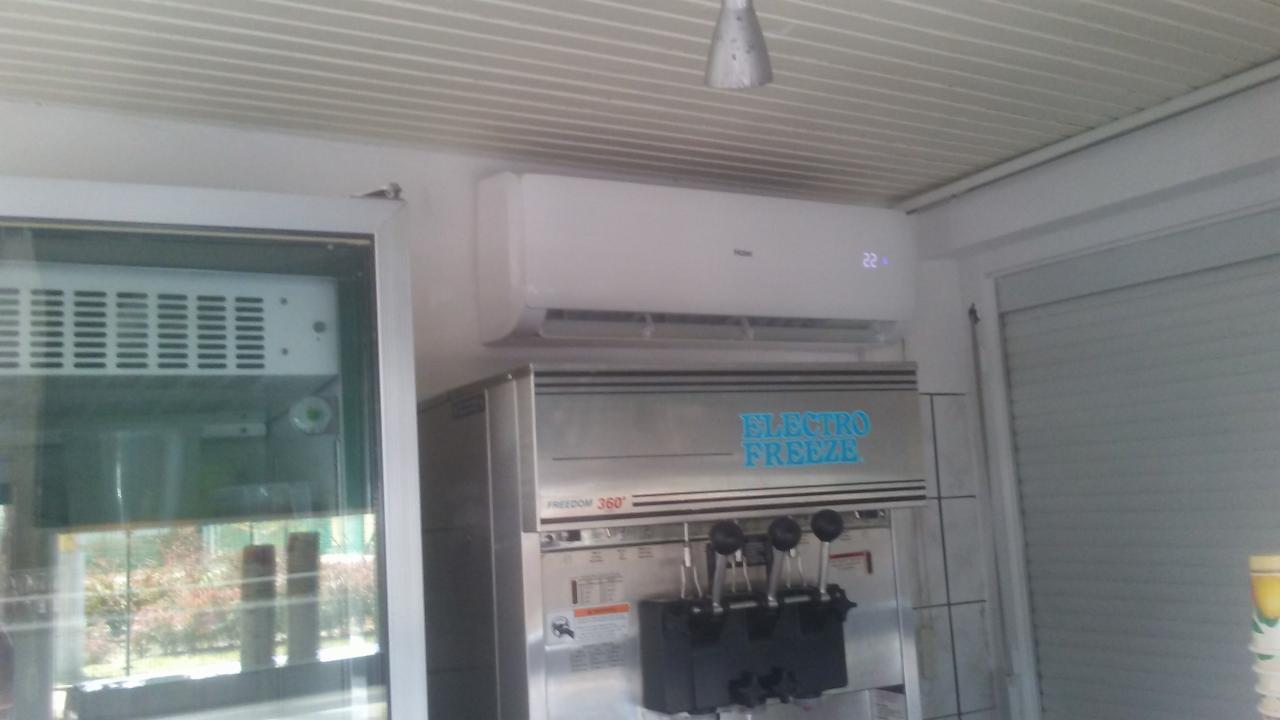 Biały klimatyzator Haier zamontowany nad maszyną do lodów Electro Freeze Freedom 360 w lokalu.