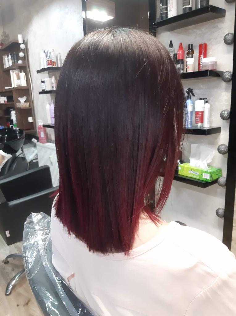 Średniej długości, proste włosy w kolorze ciemnej wiśni z widocznymi refleksami w salonie.