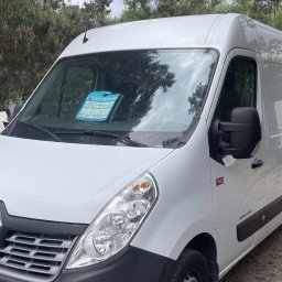 LEASING S.O.S. - Biały Renault Master, częściowo widoczny z przodu, z kartką informacyjną na przedniej szybie, stojący na szutrowym podłożu na tle drzew.